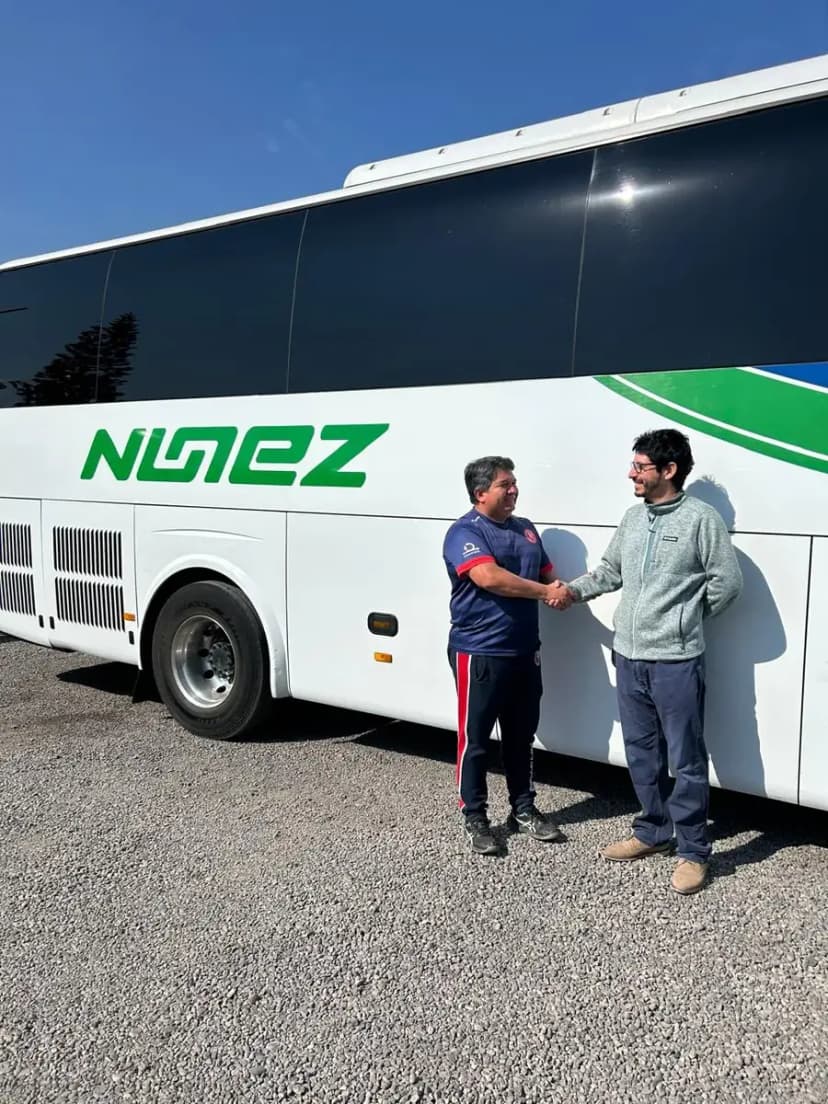 El profesor Quintanilla y Rodrigo Núñez estrechando la mano frente al bus